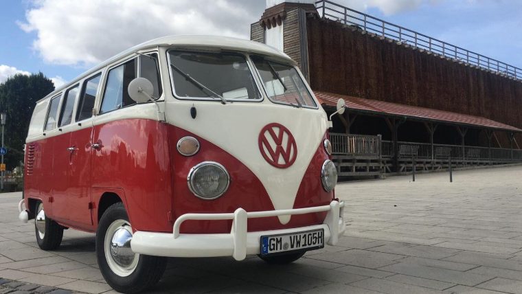 Frontansicht des Bulli Baujahr 1966 vor einem historischen Holzgebäude