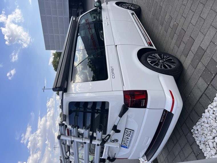 Heckansicht des VW California Coast T6.1 mit Fahrradträger und Markise