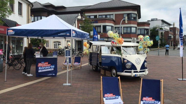 Blauer Bulli mit bunten Luftballons vor einem Volksbanken-Promotionzelt auf dem Marktplatz