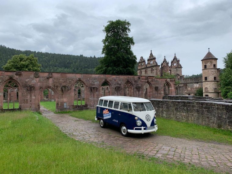 Bulli mit Volksbanken-Konzertwerbung vor einer historischen Klosterruine