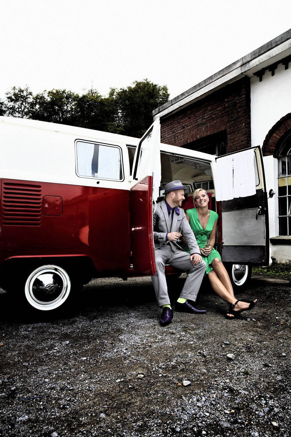 Zwei Gäste mit Sekt in der offenen Schiebetür eines VW T1 Bulli