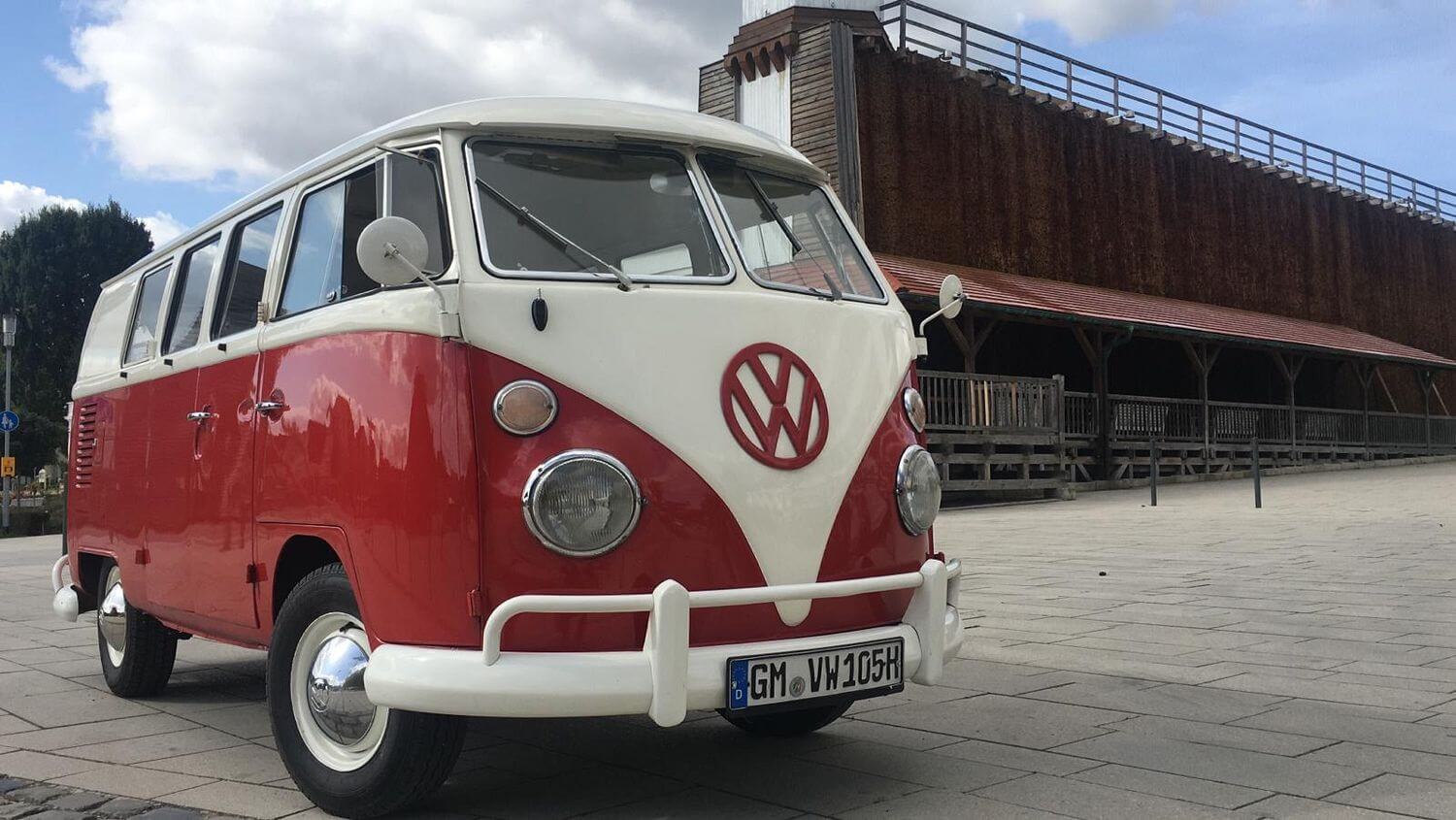 VW T1 Bulli Baujahr 1966 mit geteilter Windschutzscheibe vor einem historischen Holzgebäude