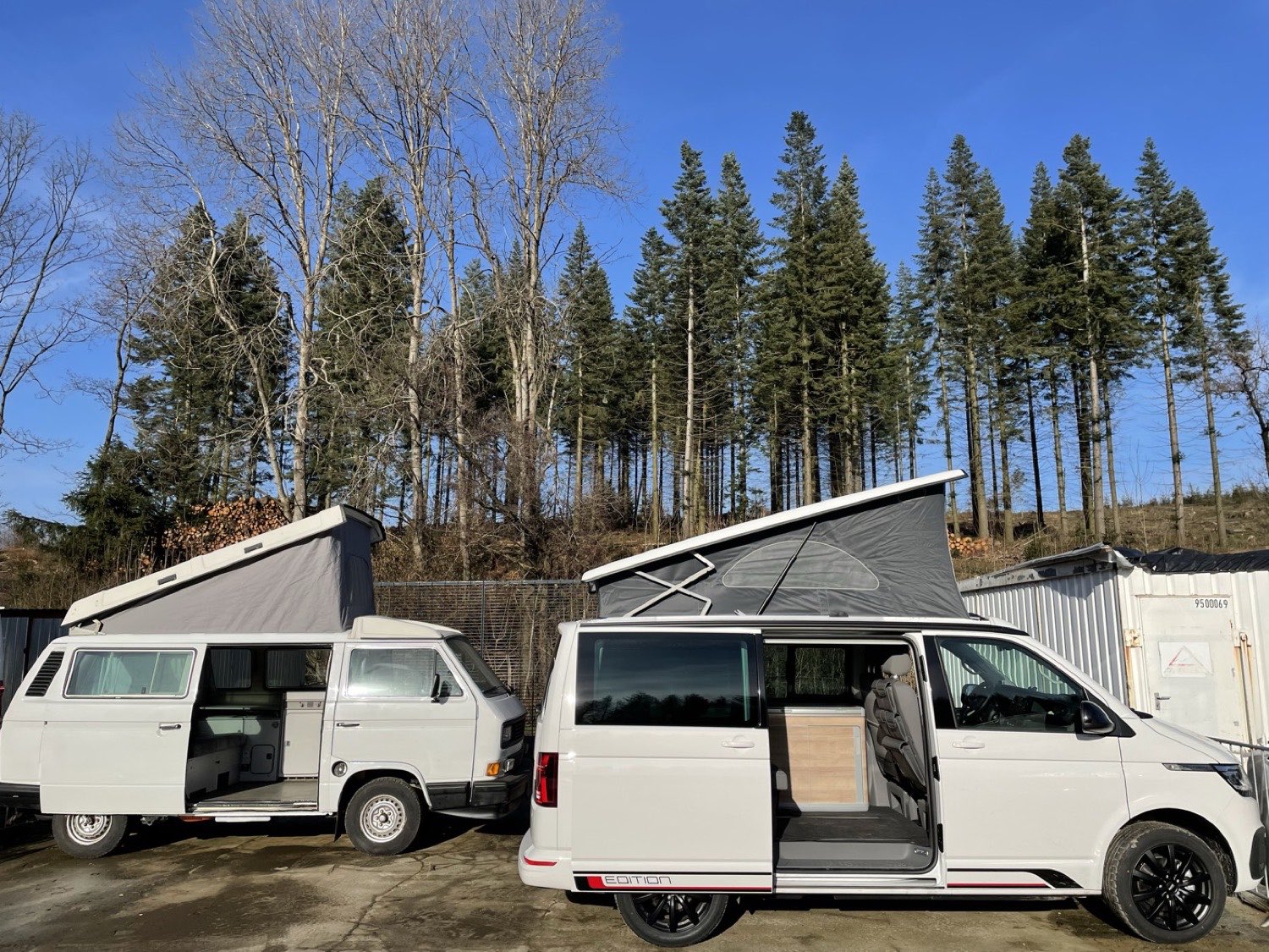 Unser weißer VW T6.1 California Coast mit geöffnetem Aufstelldach, daneben ein älterer VW T3 Camper