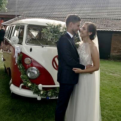 Foto vom Brautpaar vor dem dekorierten Bulli T1 1966 auf dem Hof