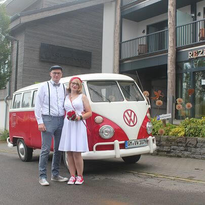 Hochzeitspaar vor dem rot-weissen Oldtimer VW Bus