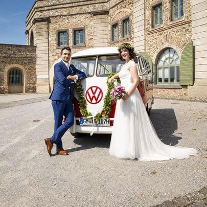 Foto-Session im Schlosshof: Brautpaar vor dem rot-weissen Oldtimer VW Bus