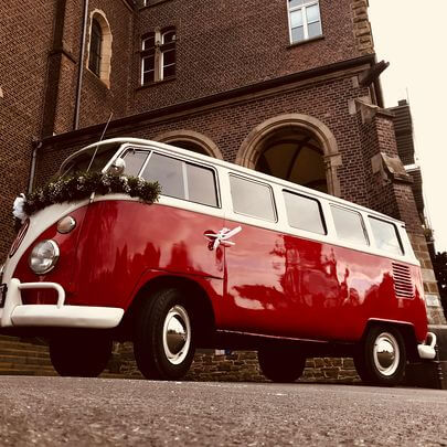 Für die Hochzeit dekorierter Oldtimer Bulli vor dem Schlosseingang wartend