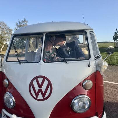 Brautpaar küsst sich auf dr vorderen Sitzbank im Hochzeits-Bulli auf der Landstrasse