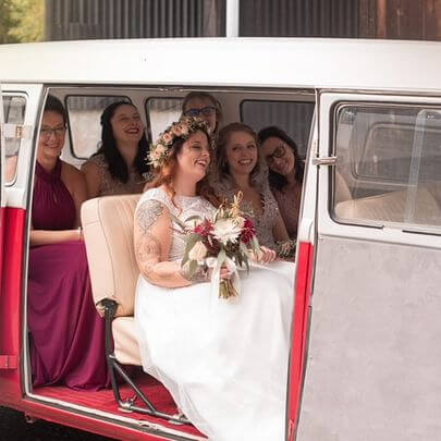 Hochzeitsbulli mit Hochzeitsgásten und Braut im Oldtimer