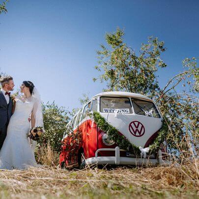Hochzeits-Foto auf dem Hügel mit Brautpaar und einem schönen Oldtimer Bulli T1 
