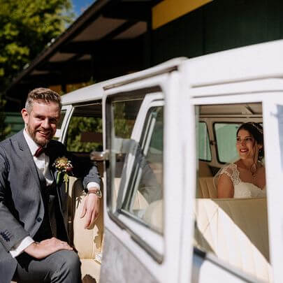 Bráutigm and der Tür und Braut im innenraum eines alten Volkswagen Bulli 1966